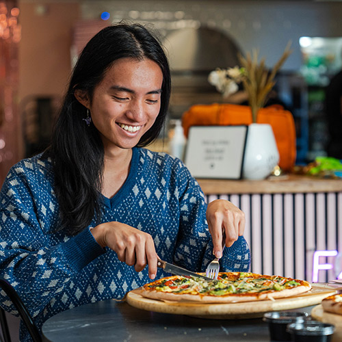 En gæst der sidder begejstret og tager en bid af en pizza fra Pop's Pizza i Ishøj.